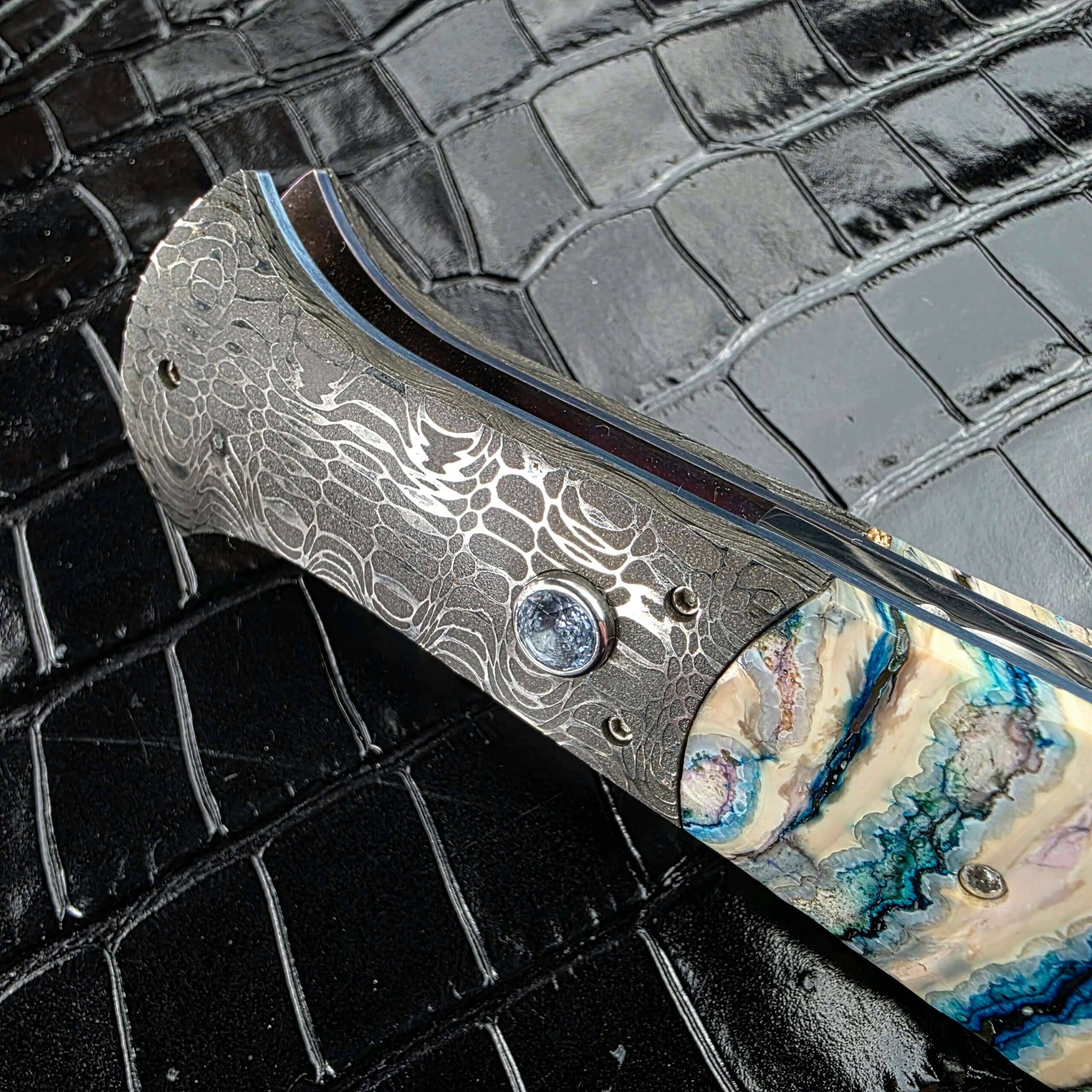 Inlaid firing button on the Damascus bolster of the Burn Knives Automatic Dagger