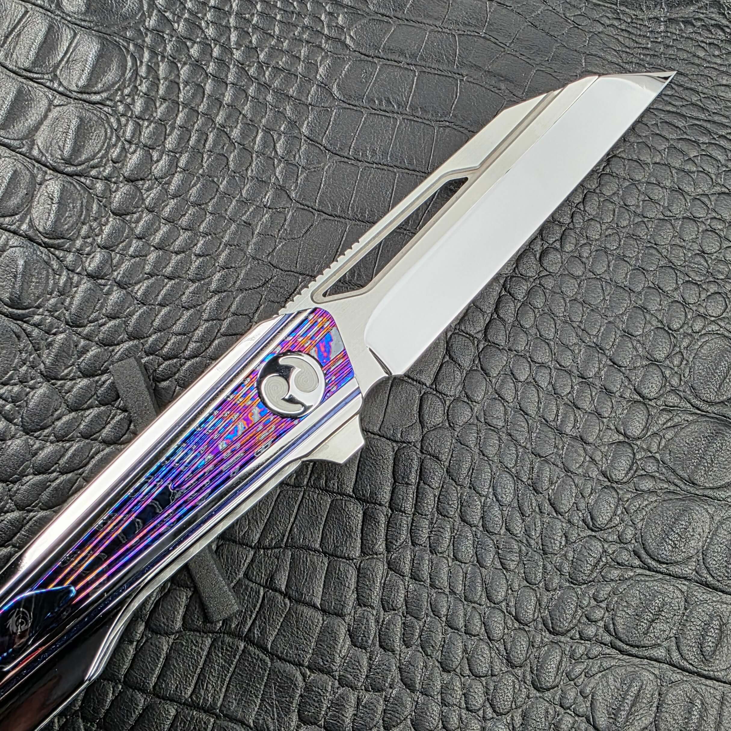 High polish M390 blade and pivot of the Dew Hara Kabuki with the Zircuti inlay behind