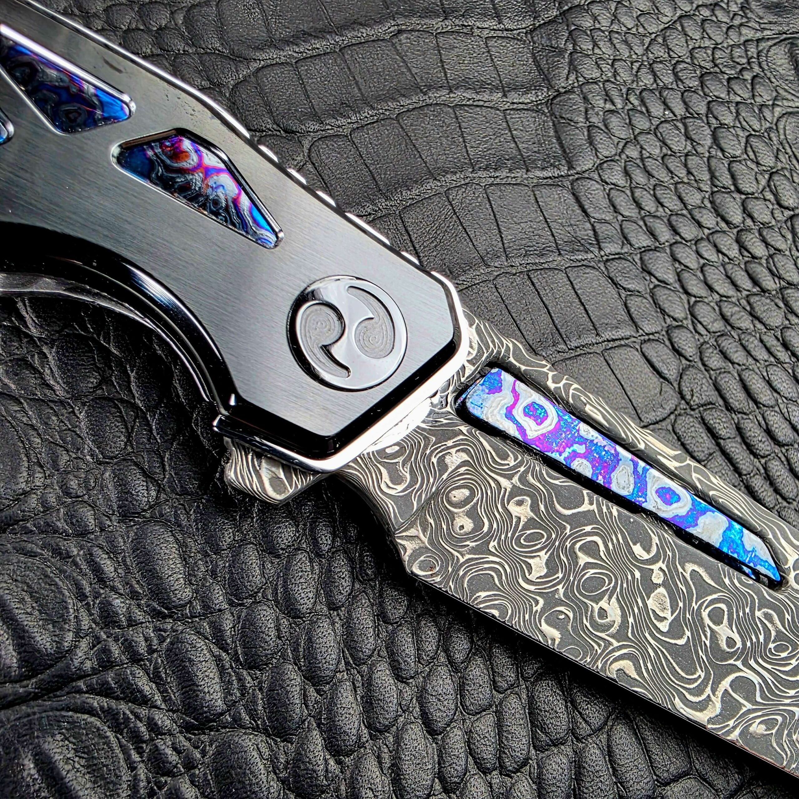 Swirl-pattern DLC pivot and Damascus flipper tab on the Dew Hara Seismic Damascus Ray