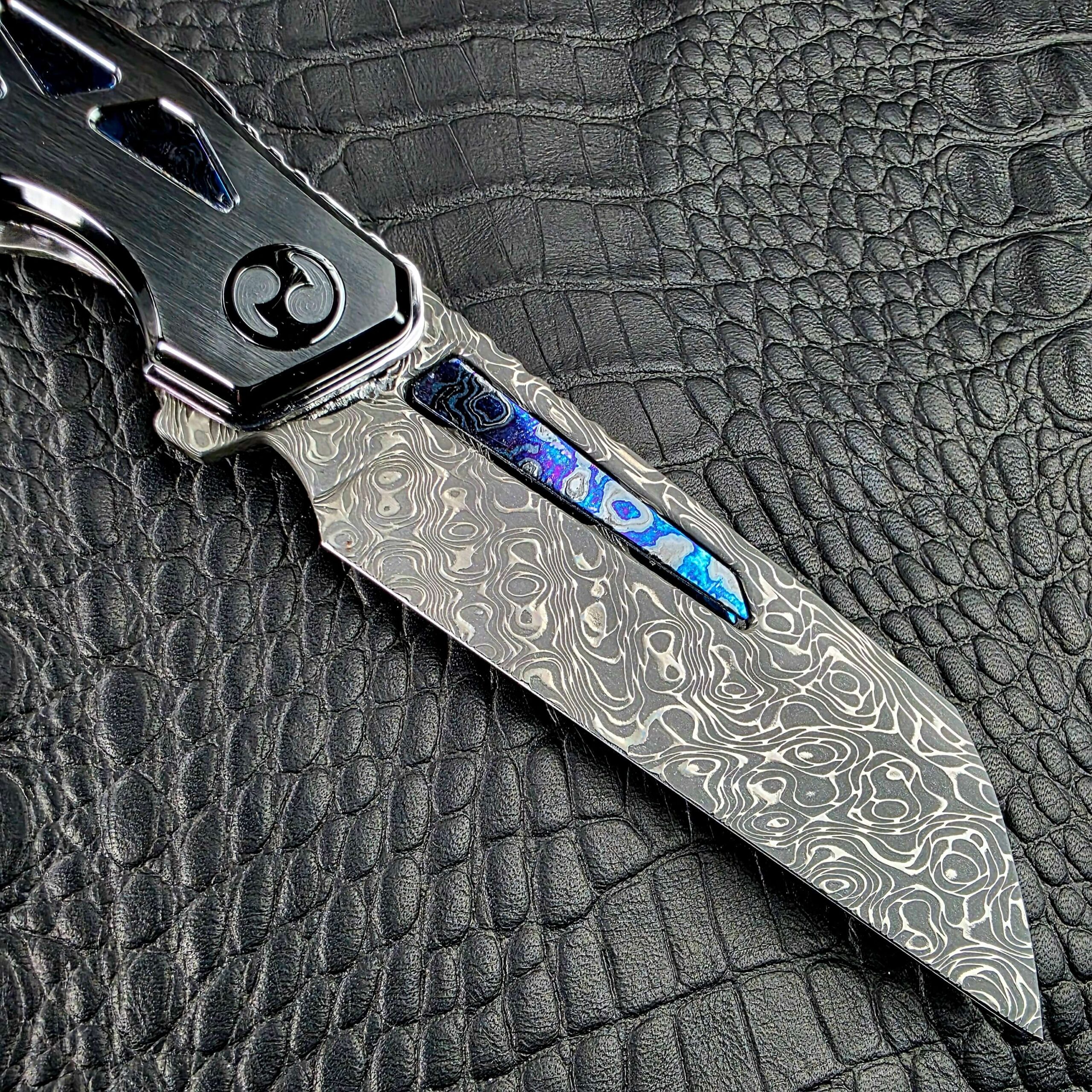Seismic Stainless Damascus Wharncliffe blade of the Dew Hara Ray with a Zircuti inlay set in the fuller