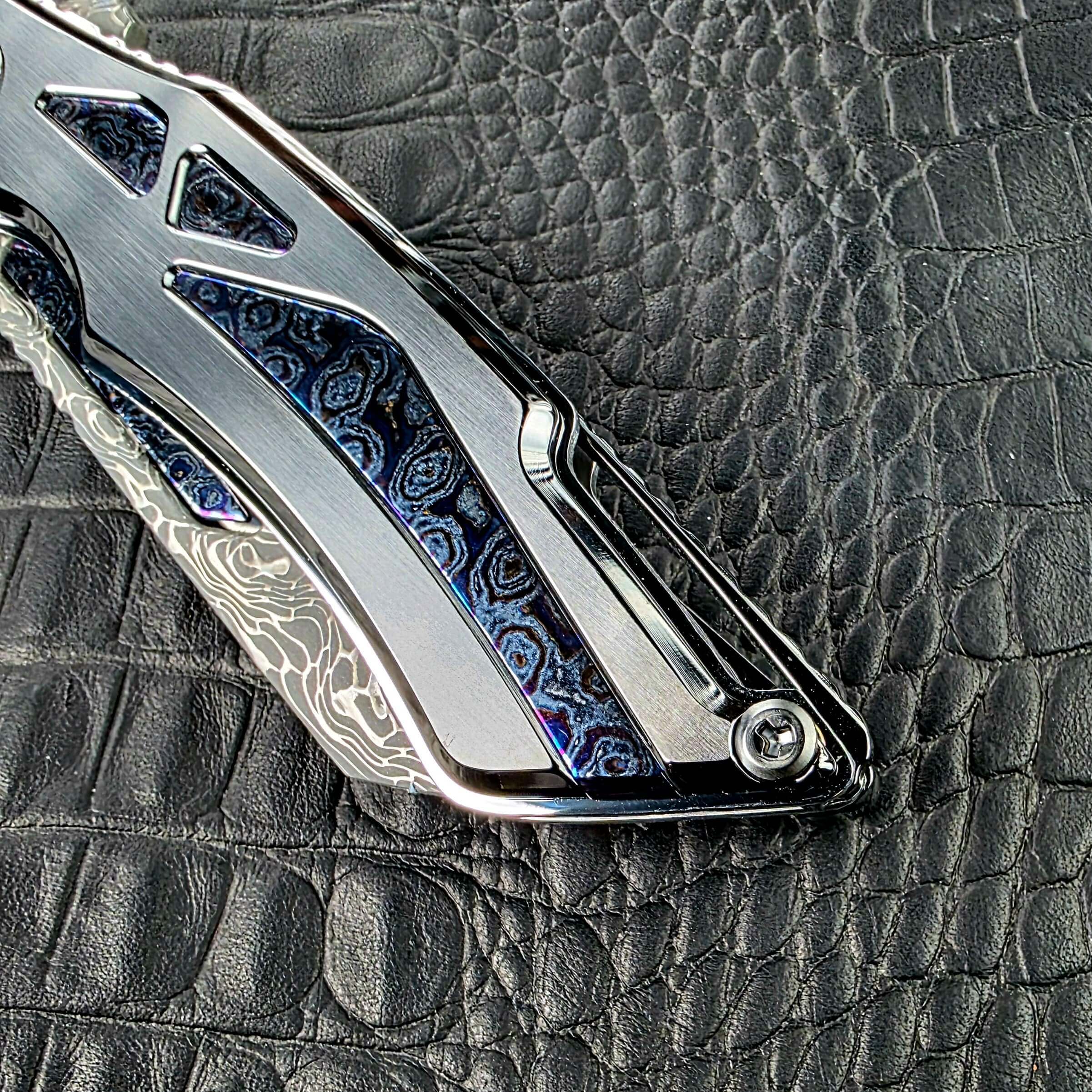 Butt end of the Dew Hara Seismic Damascus Ray showing the long Zircuti inlay and the open slot in the frame