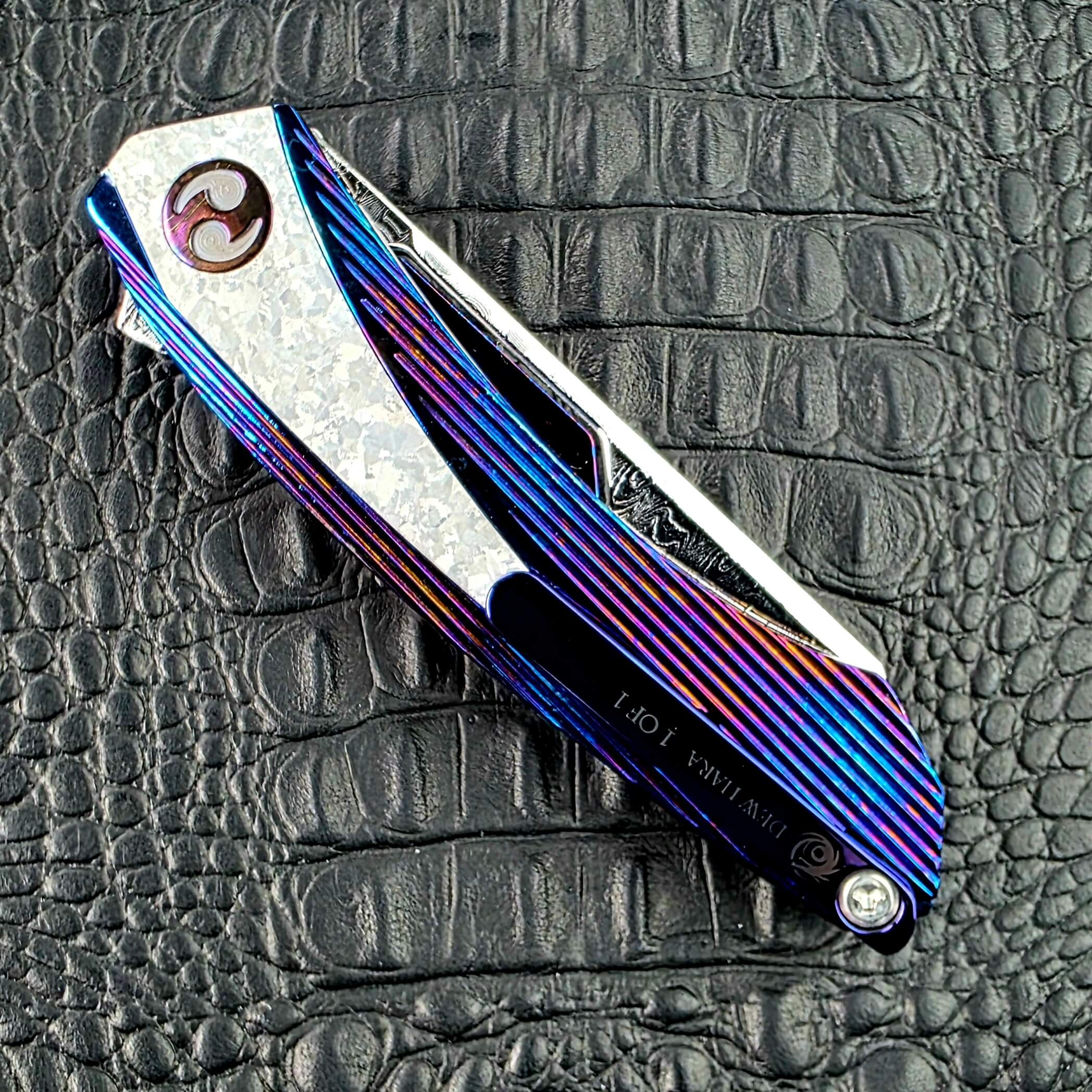 Closed Dew Hara Sharktooth Damascus METEOR on its clip side, showing the Titanium pocket clip and Crystallized Titanium panel