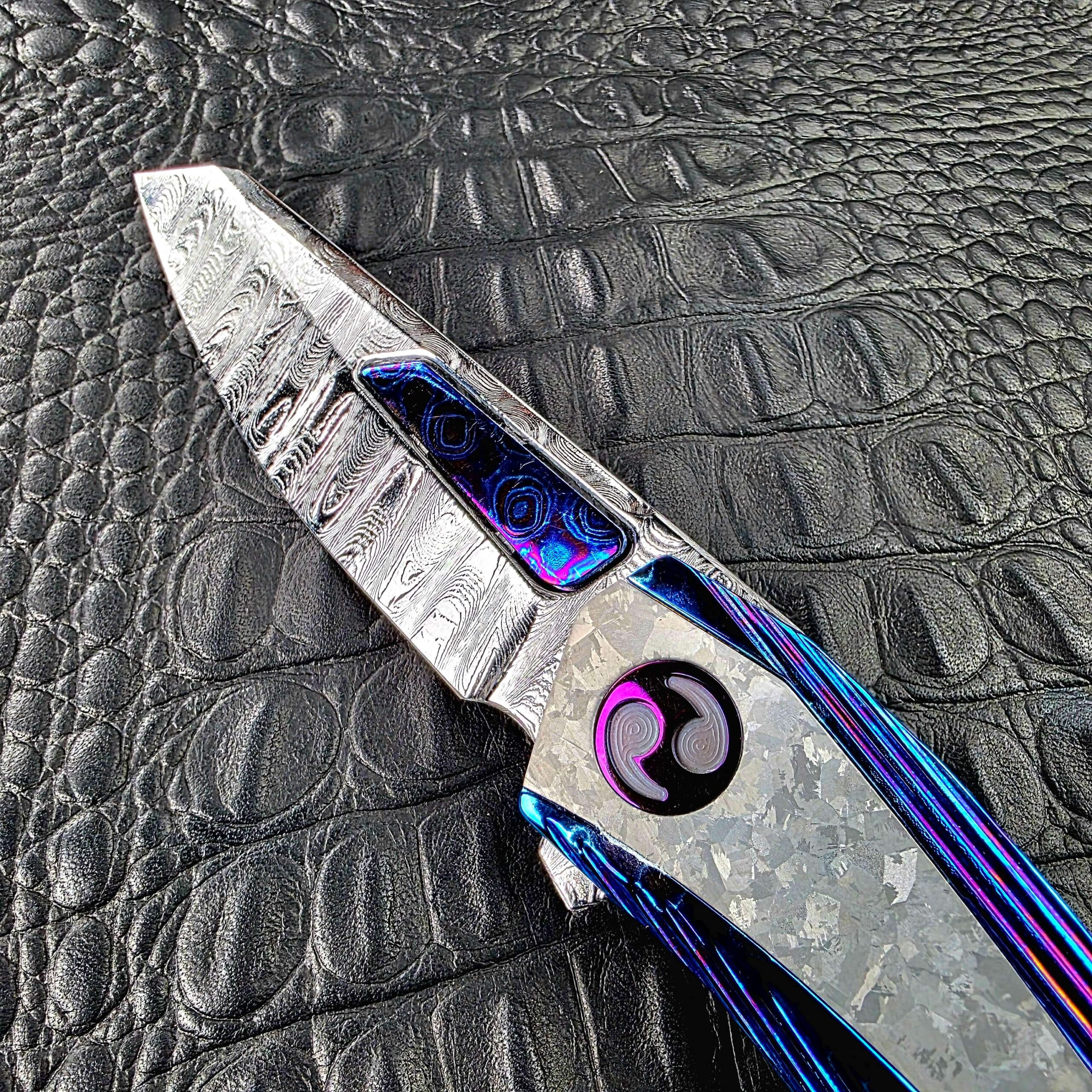 Deep etched Sharktooth Damascus blade of the Dew Hara METEOR with a Timascus inlay in the fuller