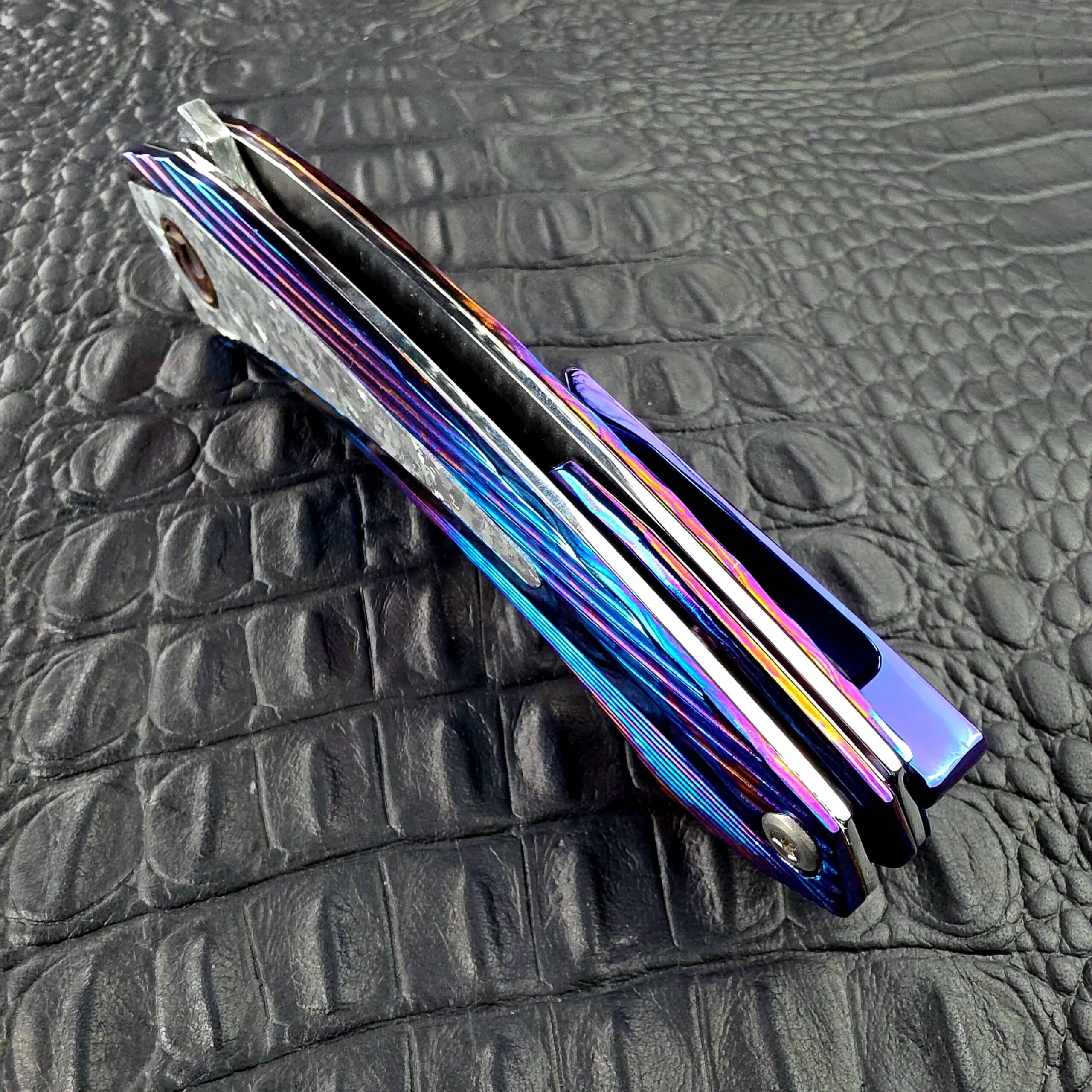 Spine view of the closed Dew Hara Sharktooth Damascus METEOR showing the Timascus backbar and pocket clip