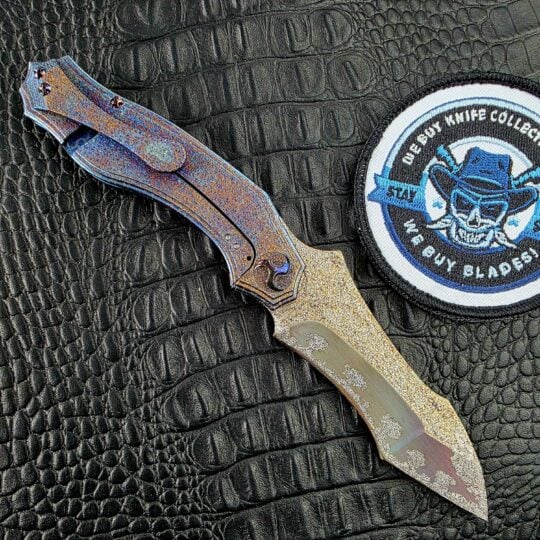 Glenn Waters Titan open on its clip side, with the milled Titanium clip and frame lock beside the We Buy Knife Collections patch