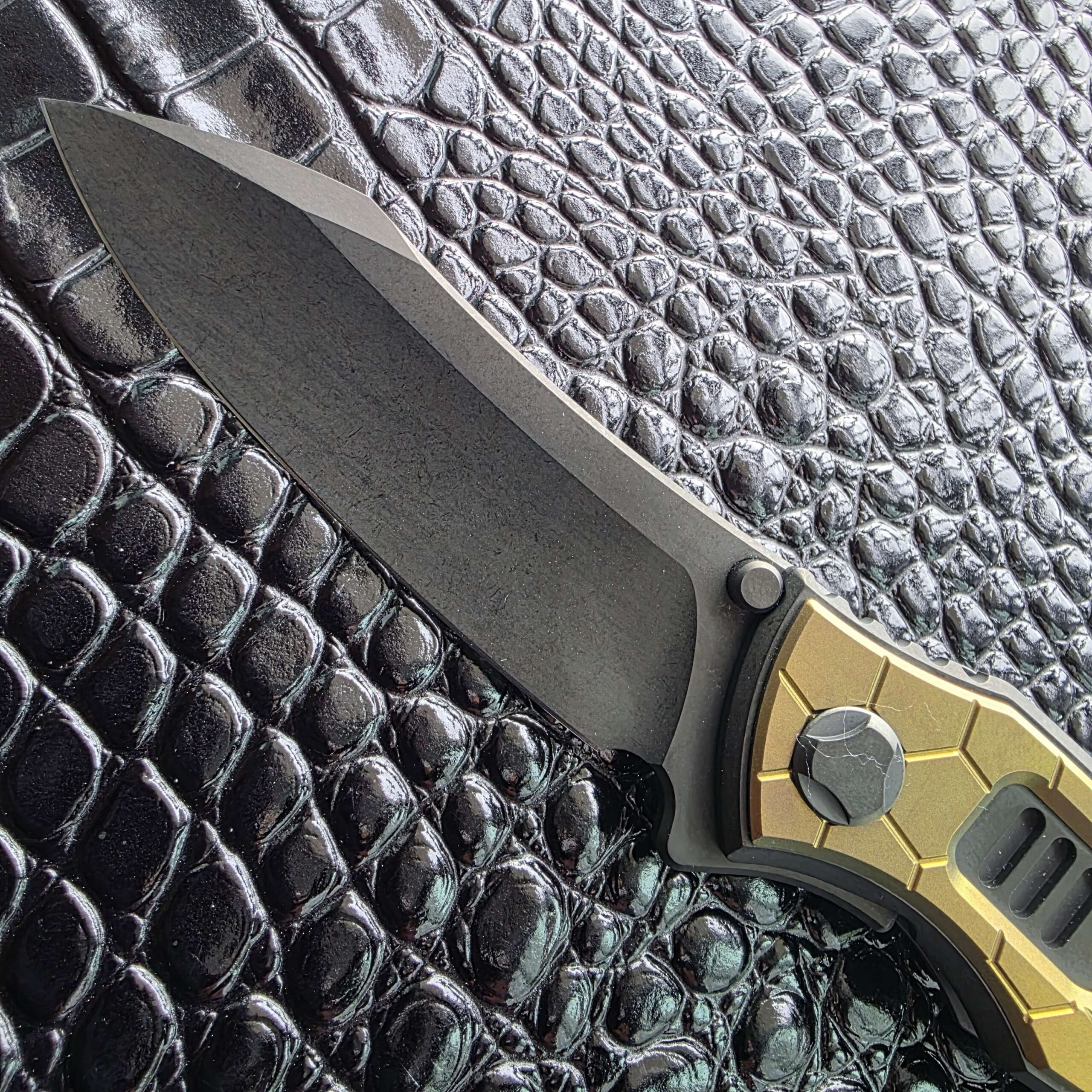 Macro of the DLC coated Bohler M390 blade on the Hawk Talon Auto showing the dark finish and stonewashed texture