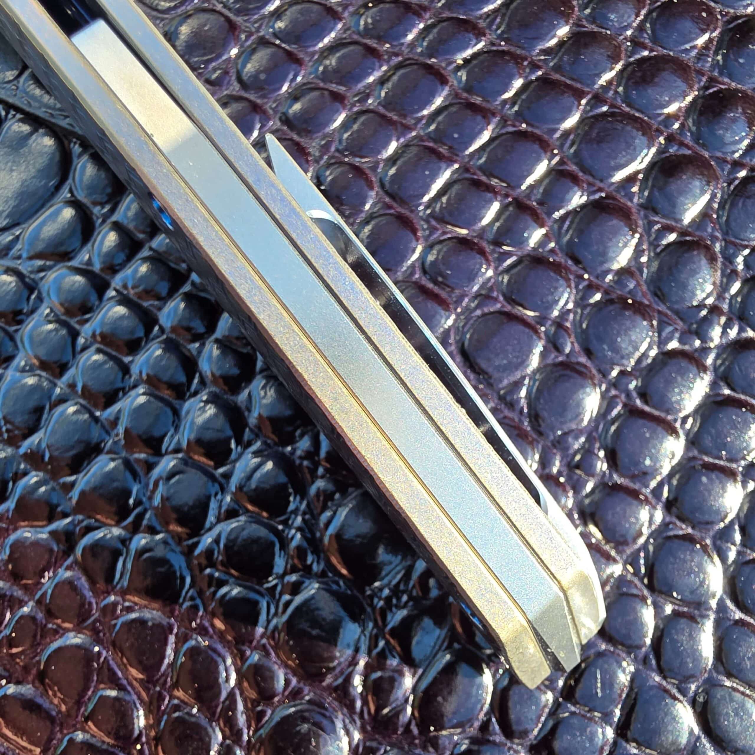 Spine view of the closed Hog House Honeycomb Model T Gen 2 showing the titanium backspacer and frame edges
