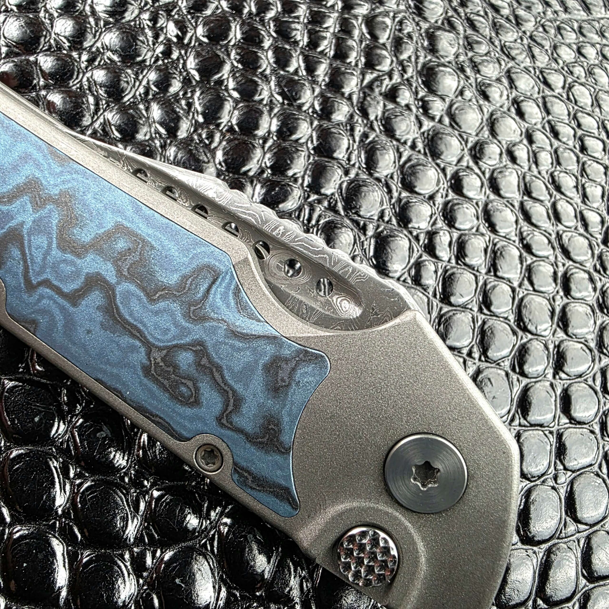 Close view of the Black Timascus inlay, pivot and push button on the closed Hypercut Dharma, show side