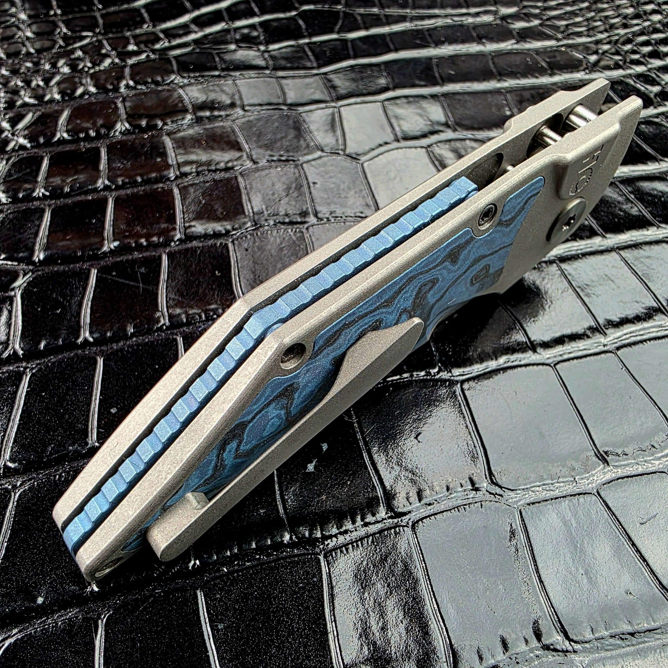 Angled view of the Hypercut Dharma’s clip side showing the blue anodized Titanium backspacer and its jimping