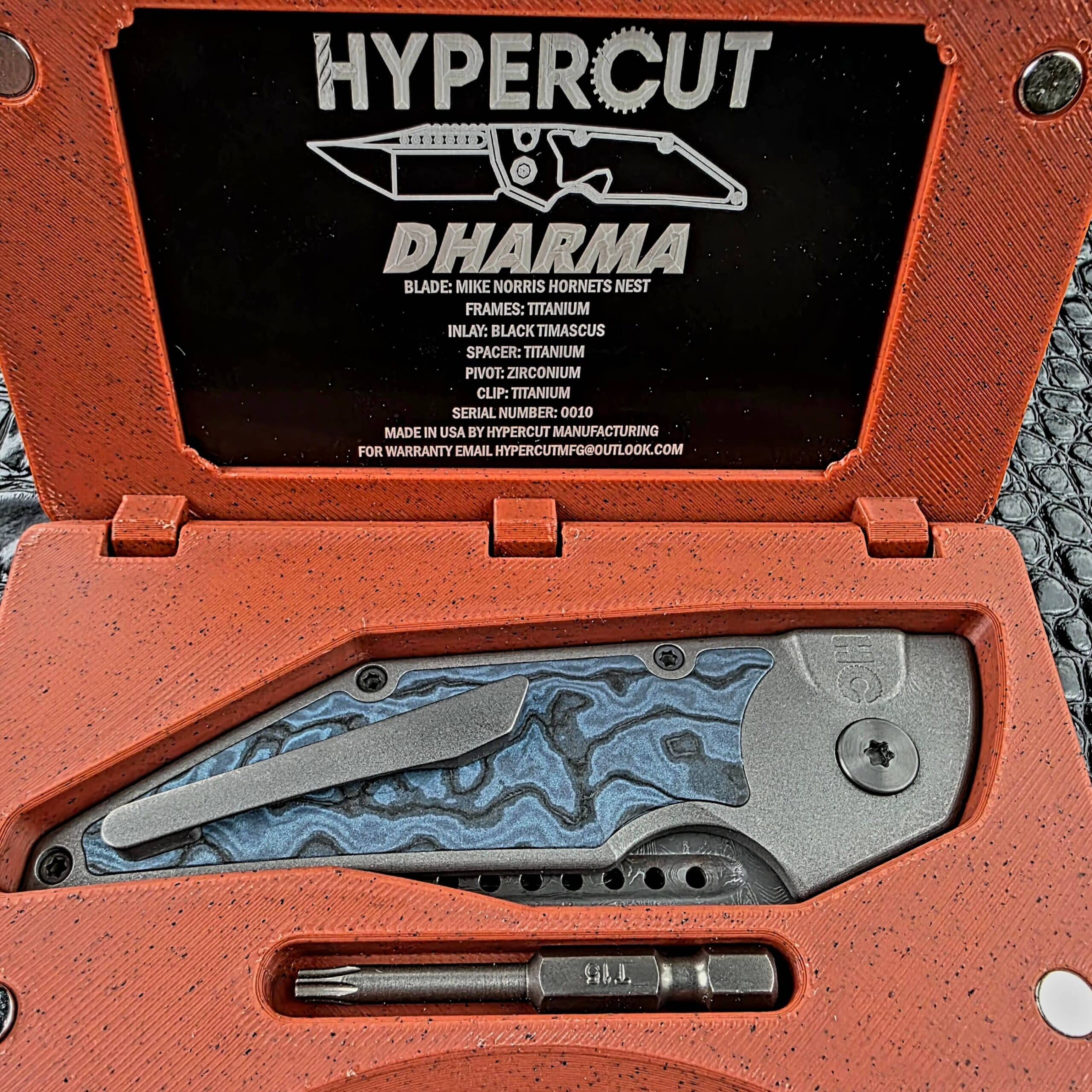 Hypercut Dharma resting clip side up in its 3D-printed case below the COA plate, with the T15 bit in its slot