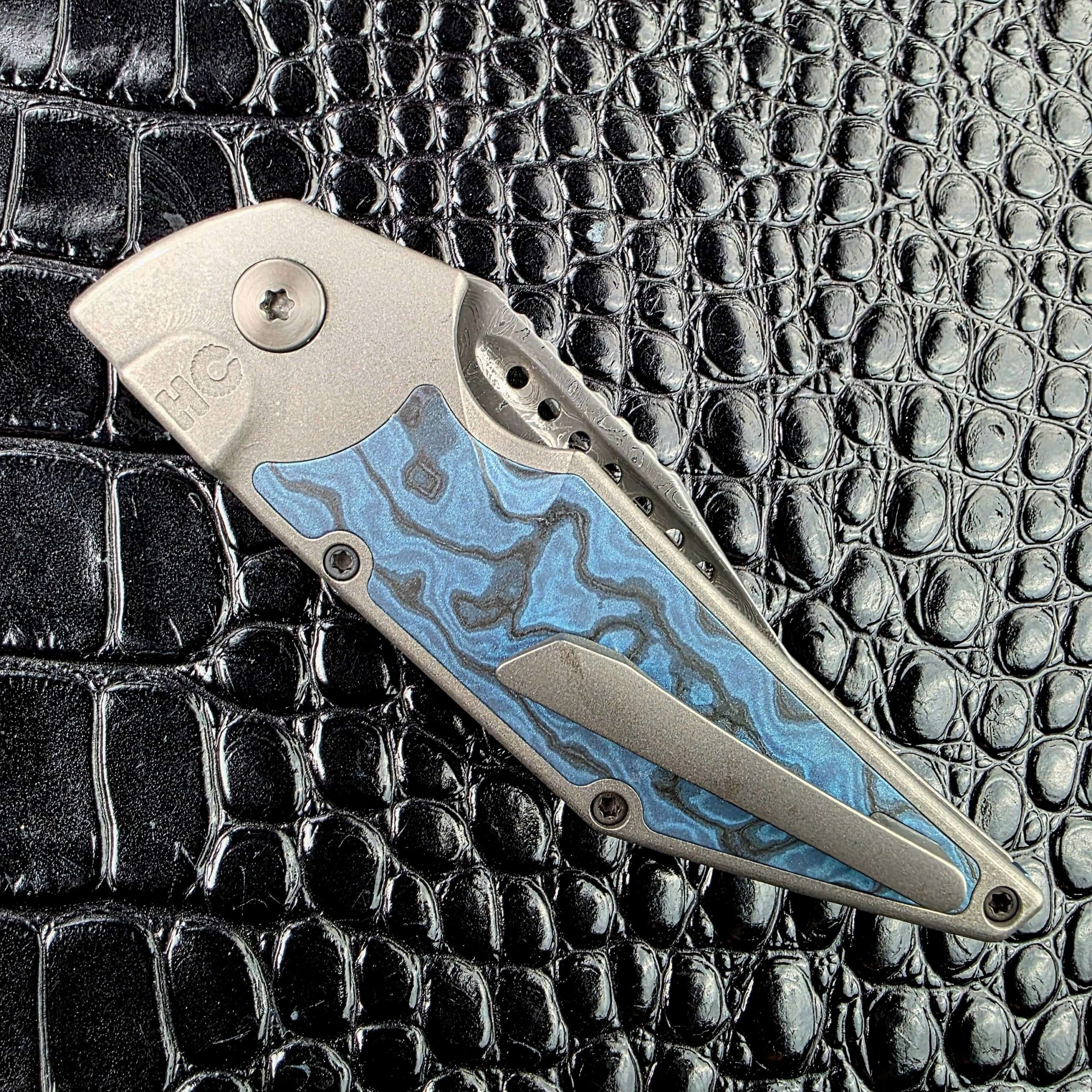 Closed Hypercut Dharma on its clip side with the HC logo, Zirconium pivot, Titanium clip and Black Timascus inlay