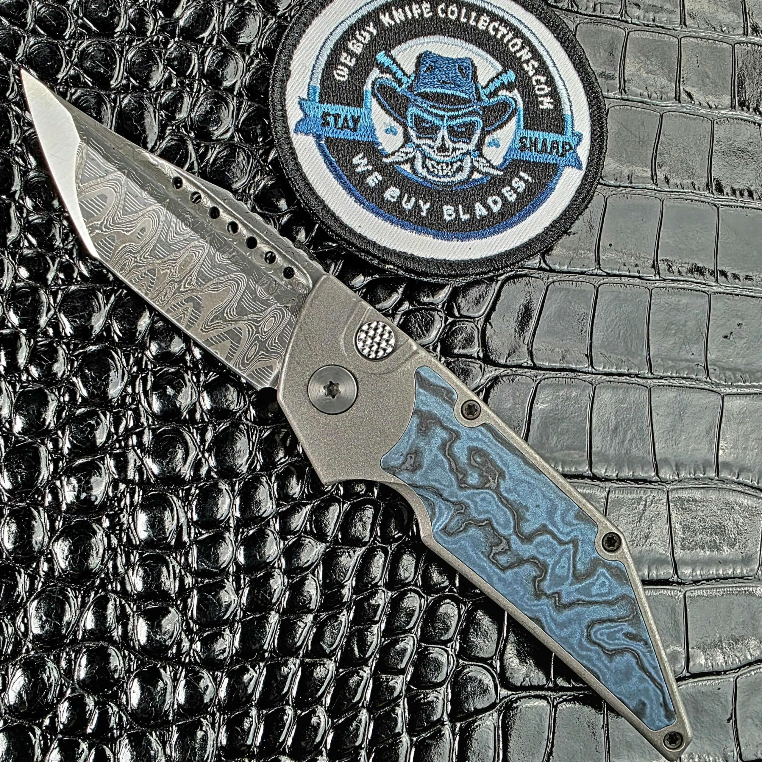 Hypercut Dharma open on its show side with a Mike Norris Hornets Nest Damascus tanto beside the We Buy Knife Collections patch