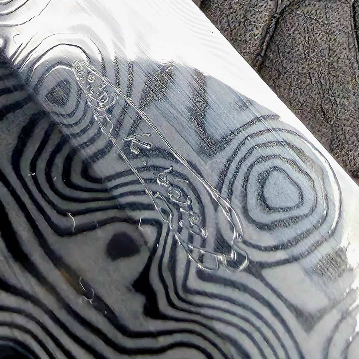 Macro of Koji Hara’s maker’s mark hand etched into the Damascus blade