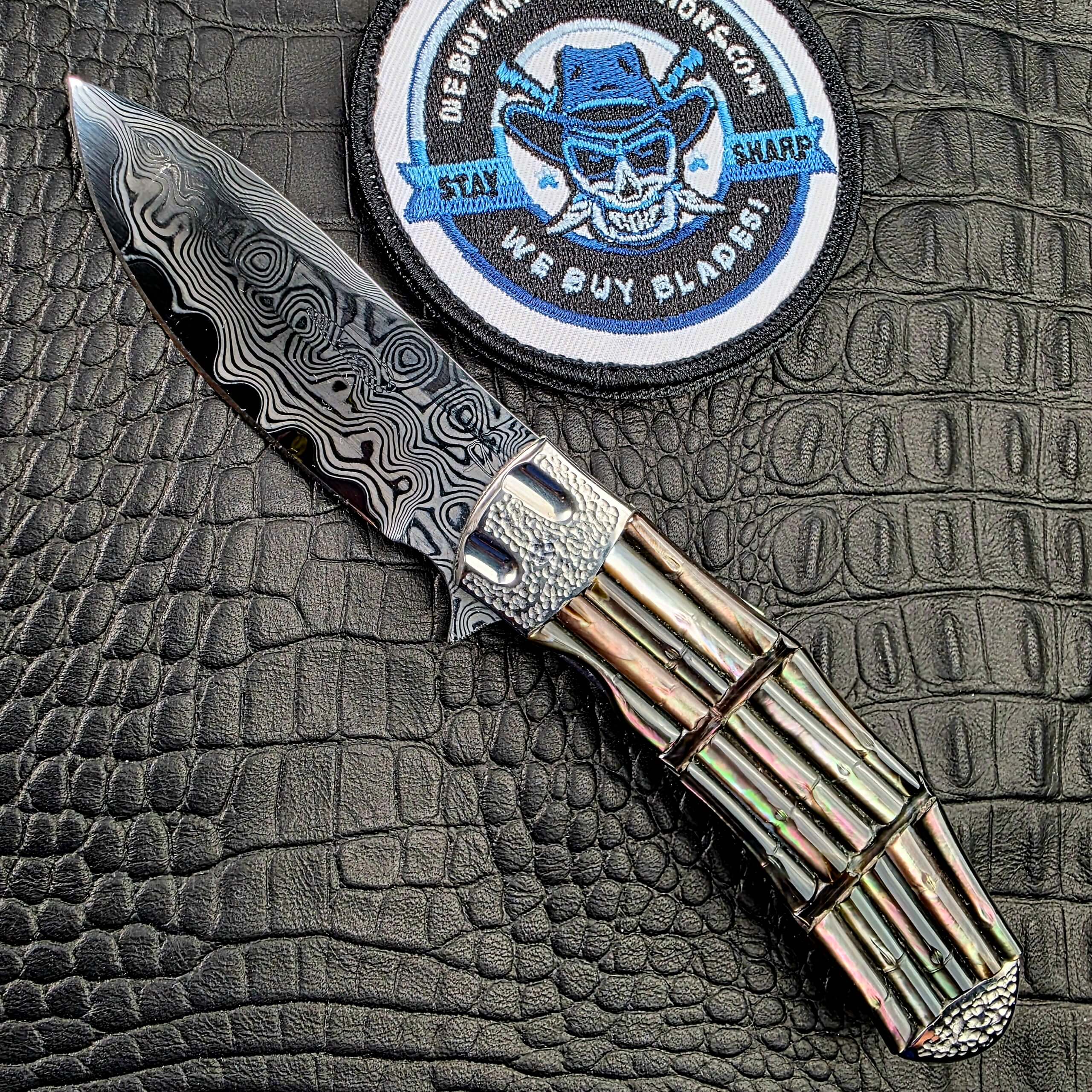 Koji Hara Take Flipper open on its show side beside the We Buy Knife Collections patch