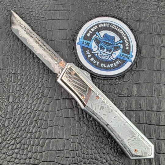Patrick Famin G.O.T.F. custom automatic open on black crocodile leather, Meteorite scale and Superconductor bolster beside the We Buy Knife Collections patch