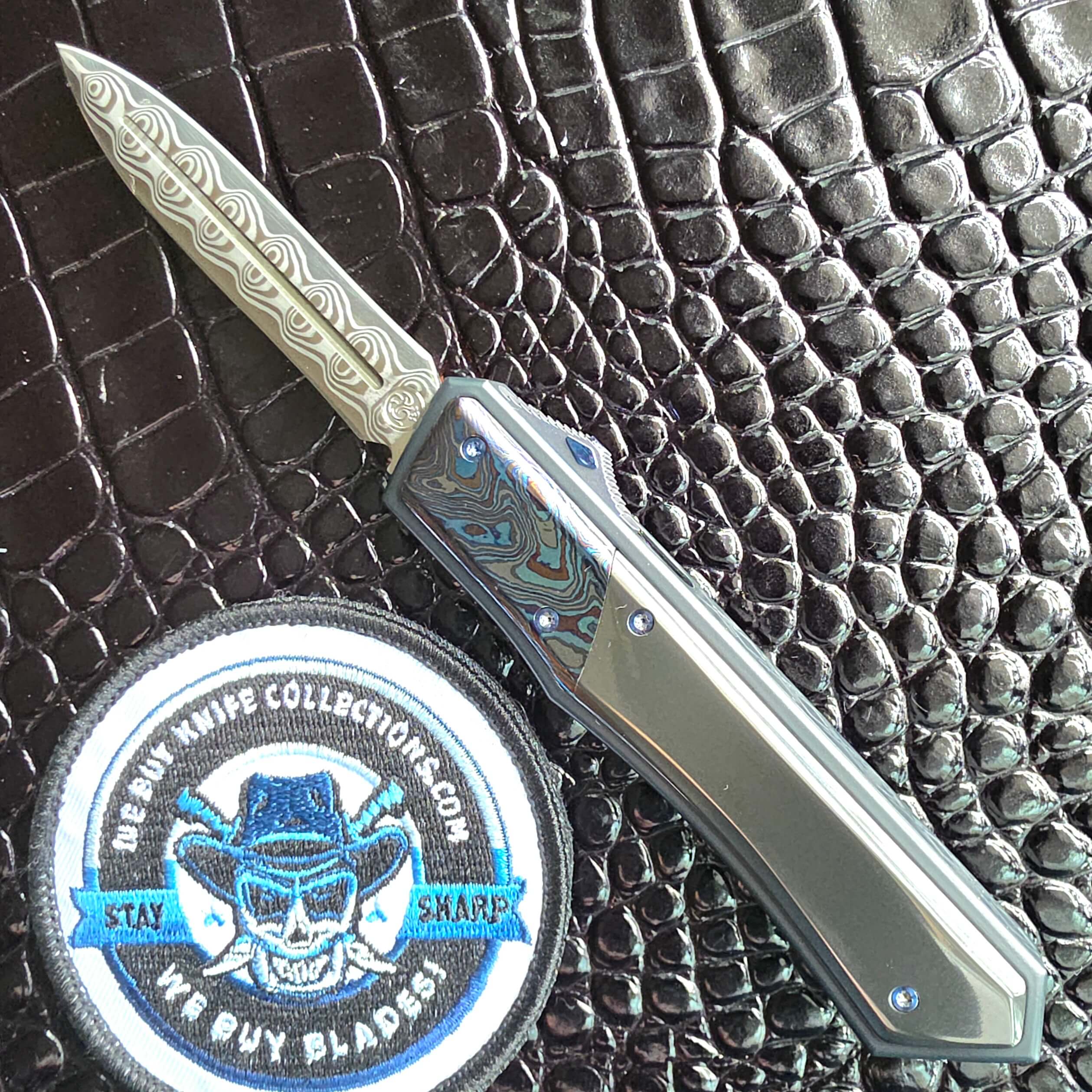 Patrick Famin GOTF Mini open on the show side with the Damasteel Damacore dagger deployed, We Buy Knife Collections patch in frame