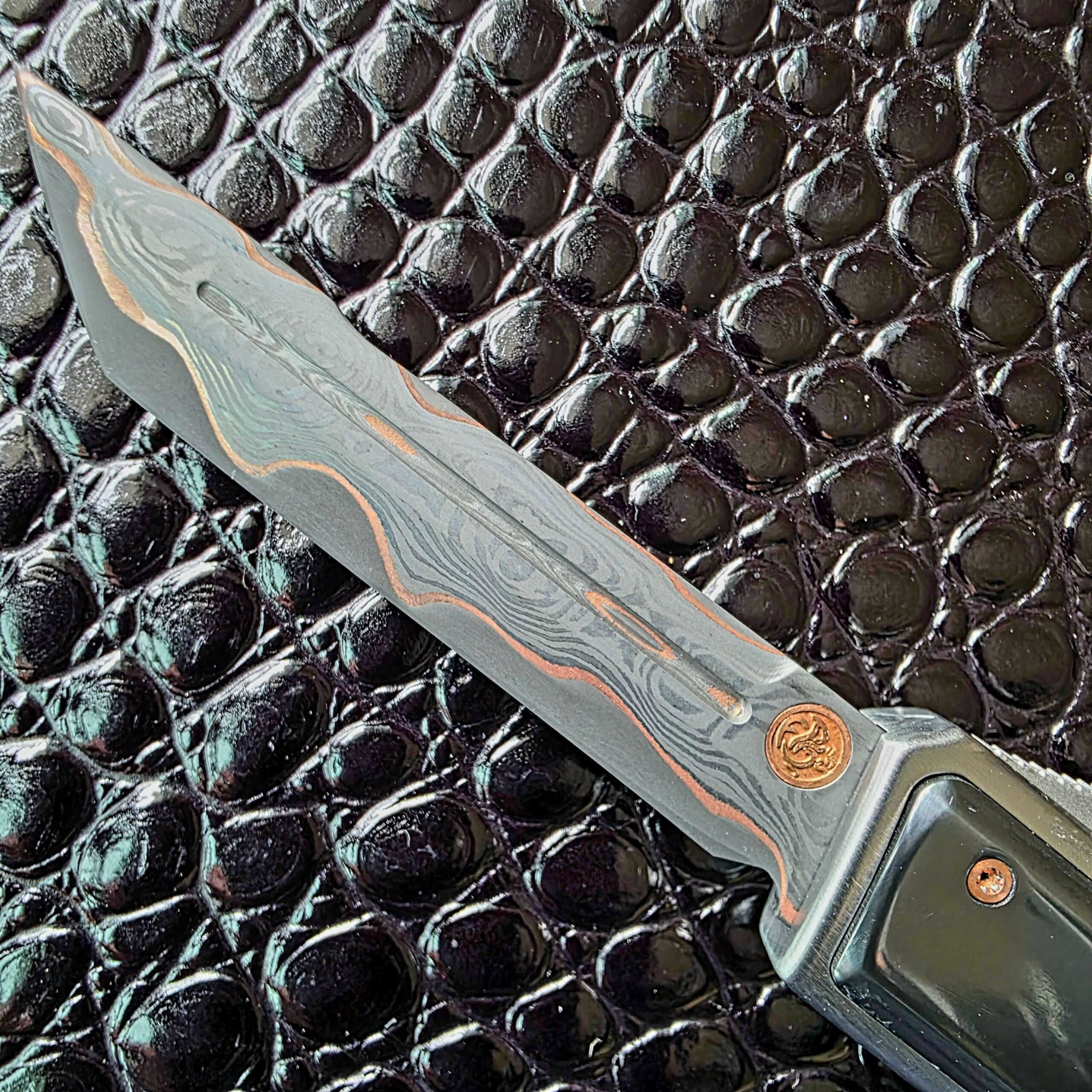 Baker Forge CopperMai copper san mai damascus blade on the Patrick Famin G.O.T.F. Mini, showing the copper seam and figured core