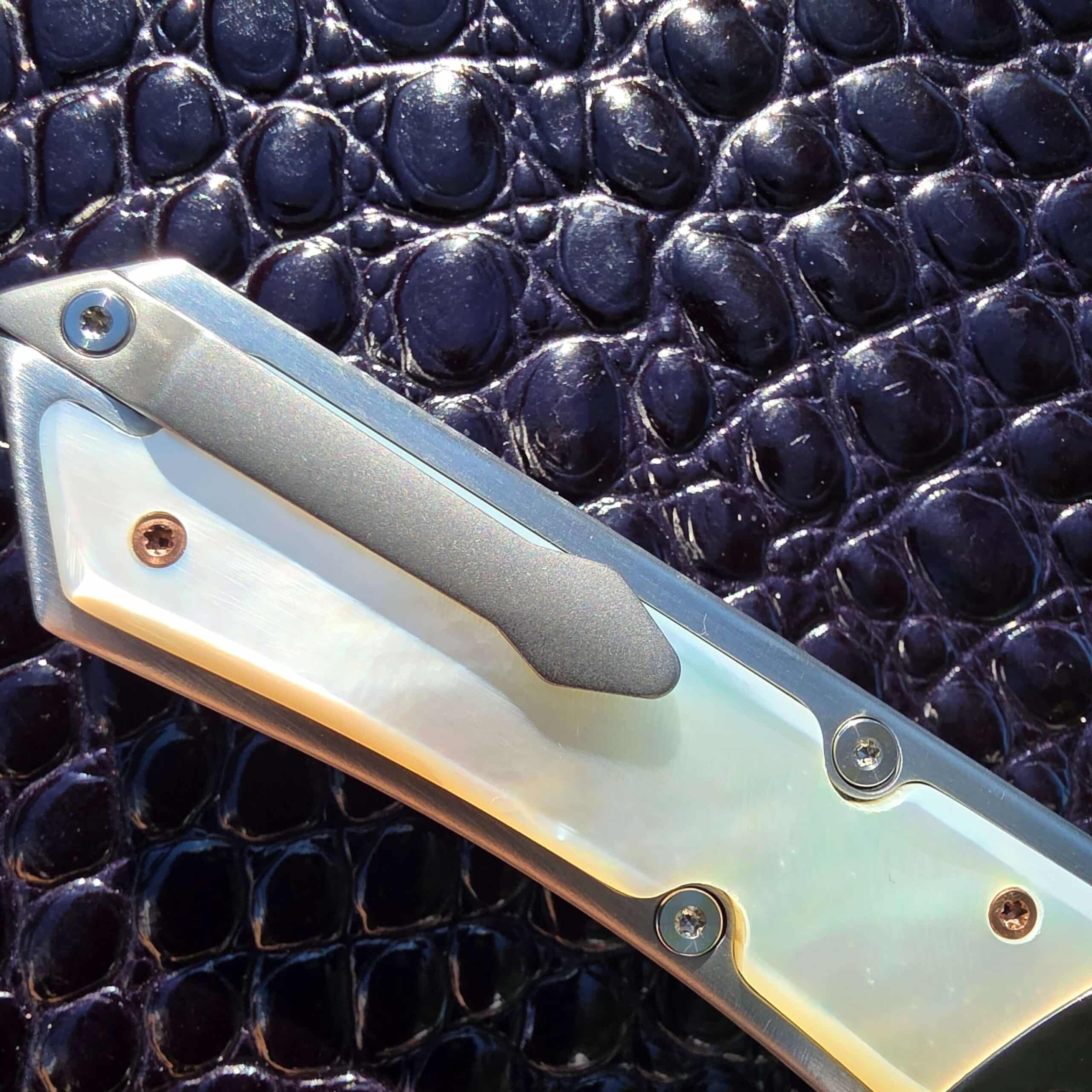 Bead-blasted titanium pocket clip over the mother of pearl scale on the Patrick Famin G.O.T.F. Mini, with mixed copper and steel hardware